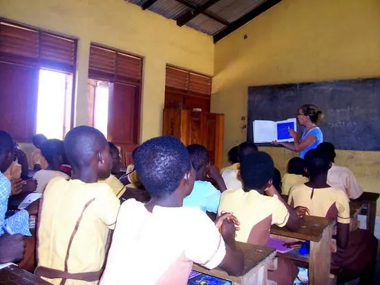 Sue volunteer teaching in Ghana, students listening attentively.