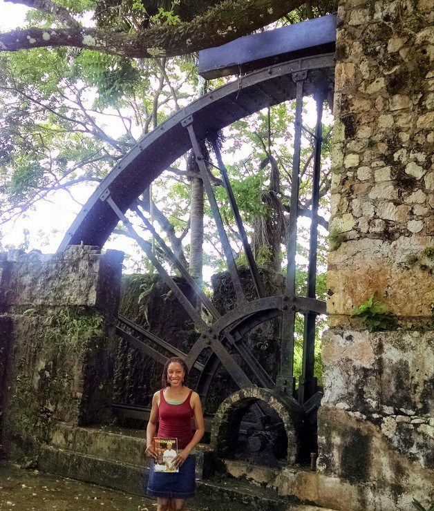 Montego Bay, Jamaica, in front of a preserved water wheel on a former sugar cane plantation. Fenesha is holding the Toastmasters magazine for the Traveling Toastmaster feature.