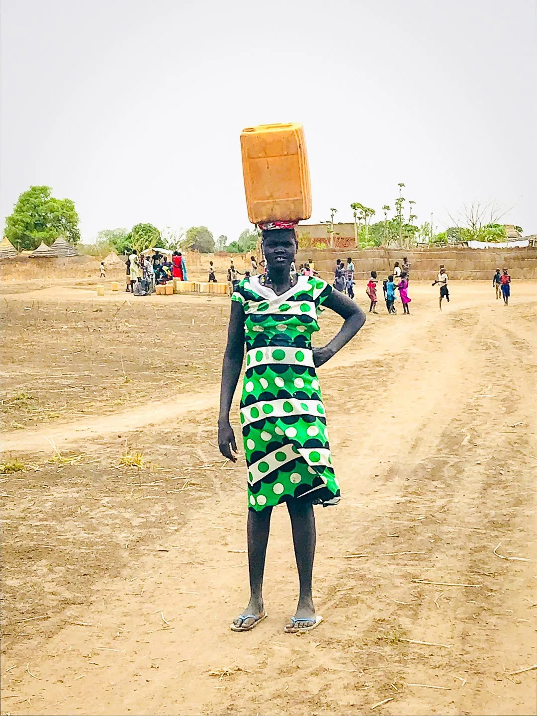 A girl in South Sudan carrying water on her head.